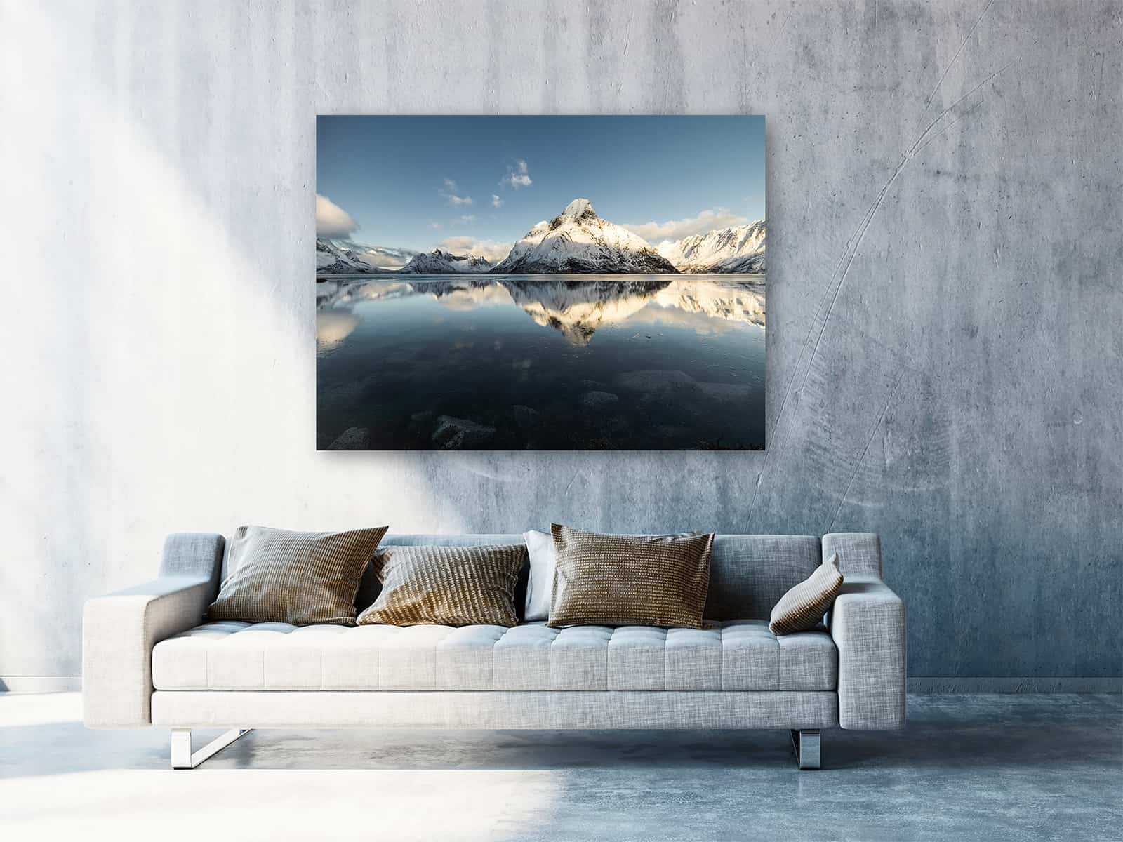 Der ChromaLuxe Print "Arctic Mountains" hängt in einem hellen, freundlichem Raum. Über der modernen Couch kommt die Landschaftsfotografie besonders gut zur Geltung.