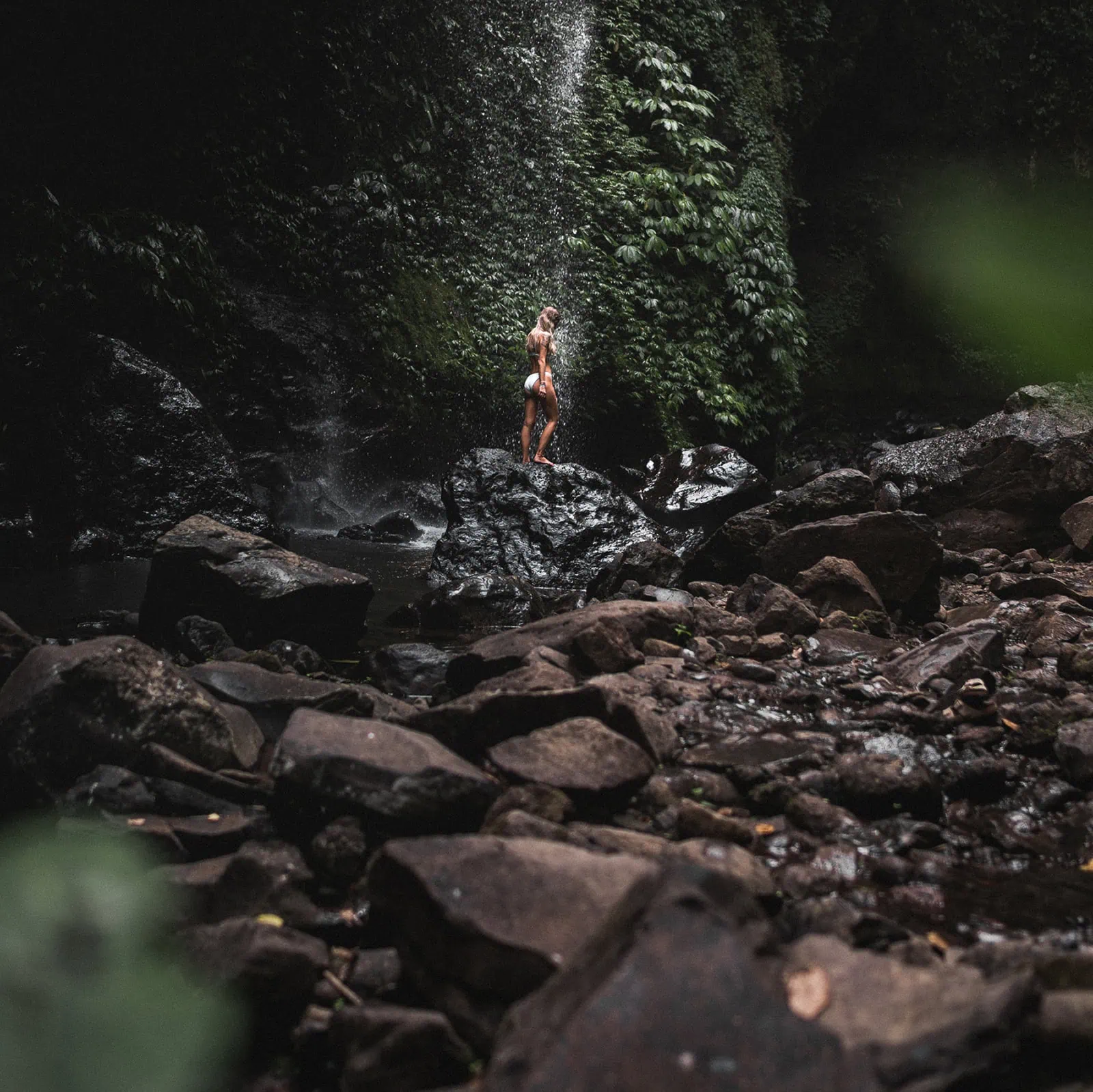Frau vor Wasserfall im tief grünen Jungle von Bali.