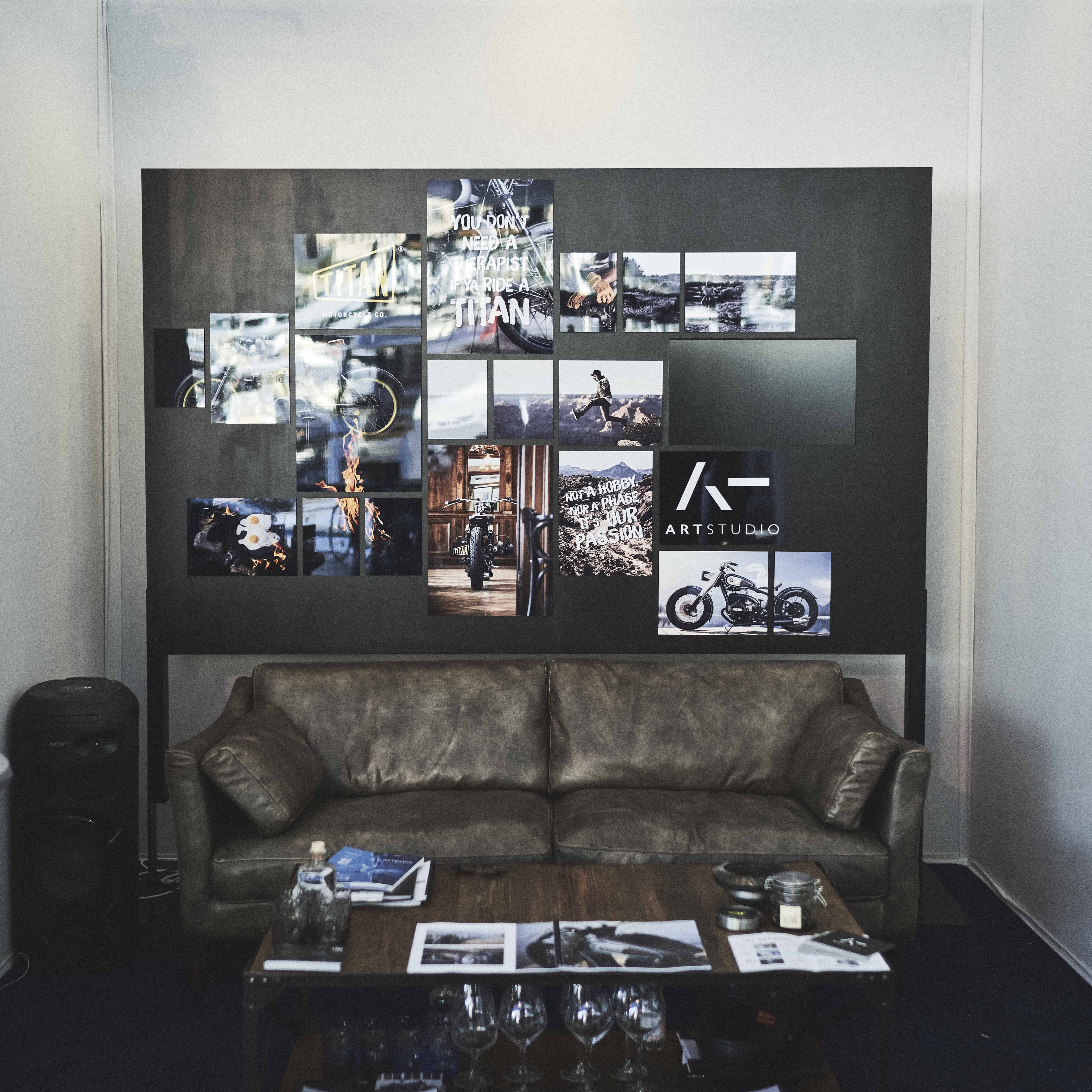 Eine schwarze Tafel mit Bildern davor steht ein Holztisch und eine braune Ledercouch