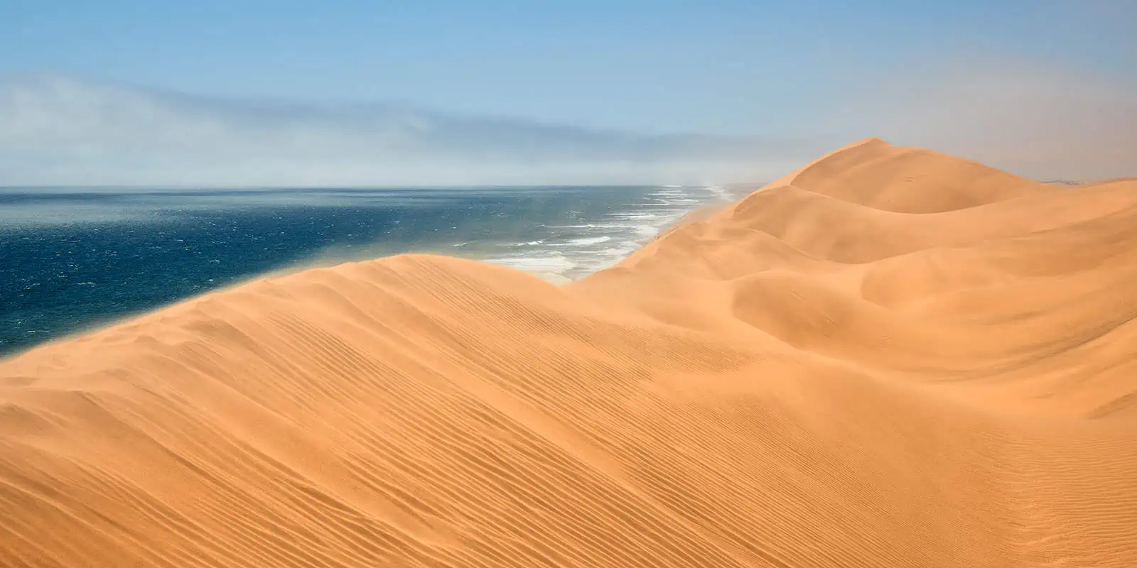 "Painted Dunes"orange Wüstendüne im HIntergrund das dunkelblaue Meer